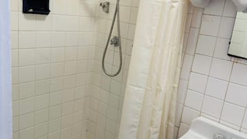 A small bathroom with a shower, a sink, and a tiled floor.