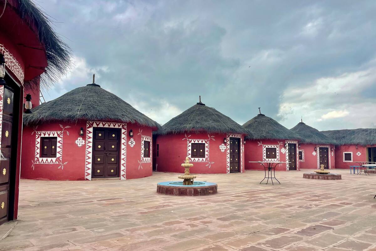 Une cour bordée de bâtiments traditionnels aux toits rouges, avec une fontaine centrale et un sol pavé.