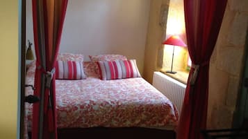 A bedroom with a bed, curtains, a lamp, and a radiator.