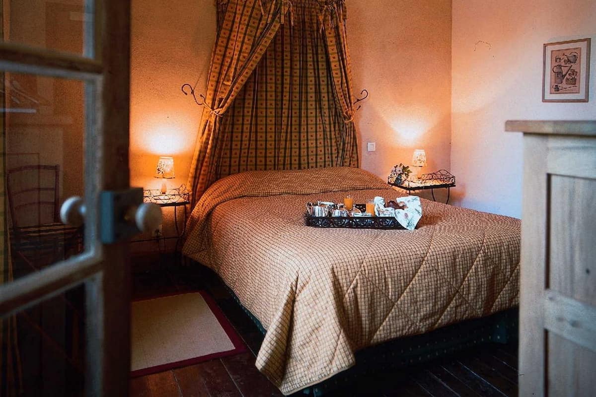 A bedroom with a bed, a bedside table, a lamp, and a framed picture on the wall.