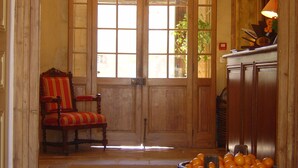 Una puerta de madera con paneles de vidrio, una silla tapizada en rojo y un cubo de naranjas.