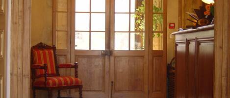 A wooden door with glass panels, a red upholstered chair, and a bucket of oranges.