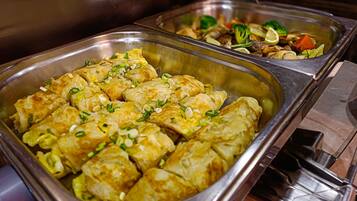 A buffet with various dishes including a tray of stuffed vegetables and another with mixed vegetables and meat.