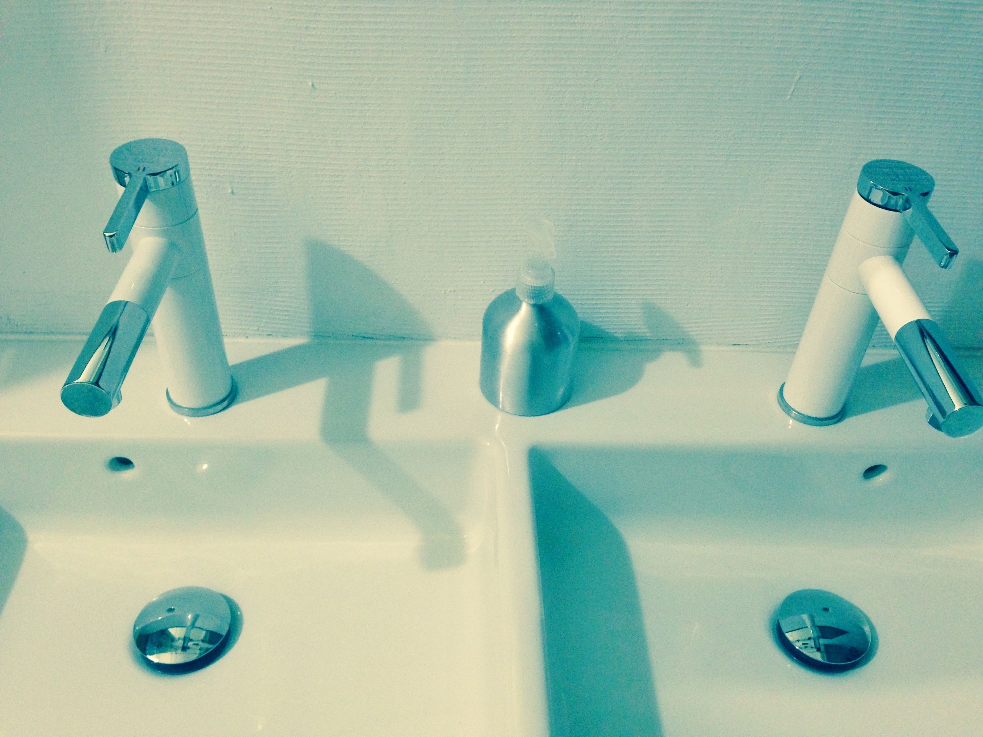 A bathroom sink with two faucets and a soap dispenser.