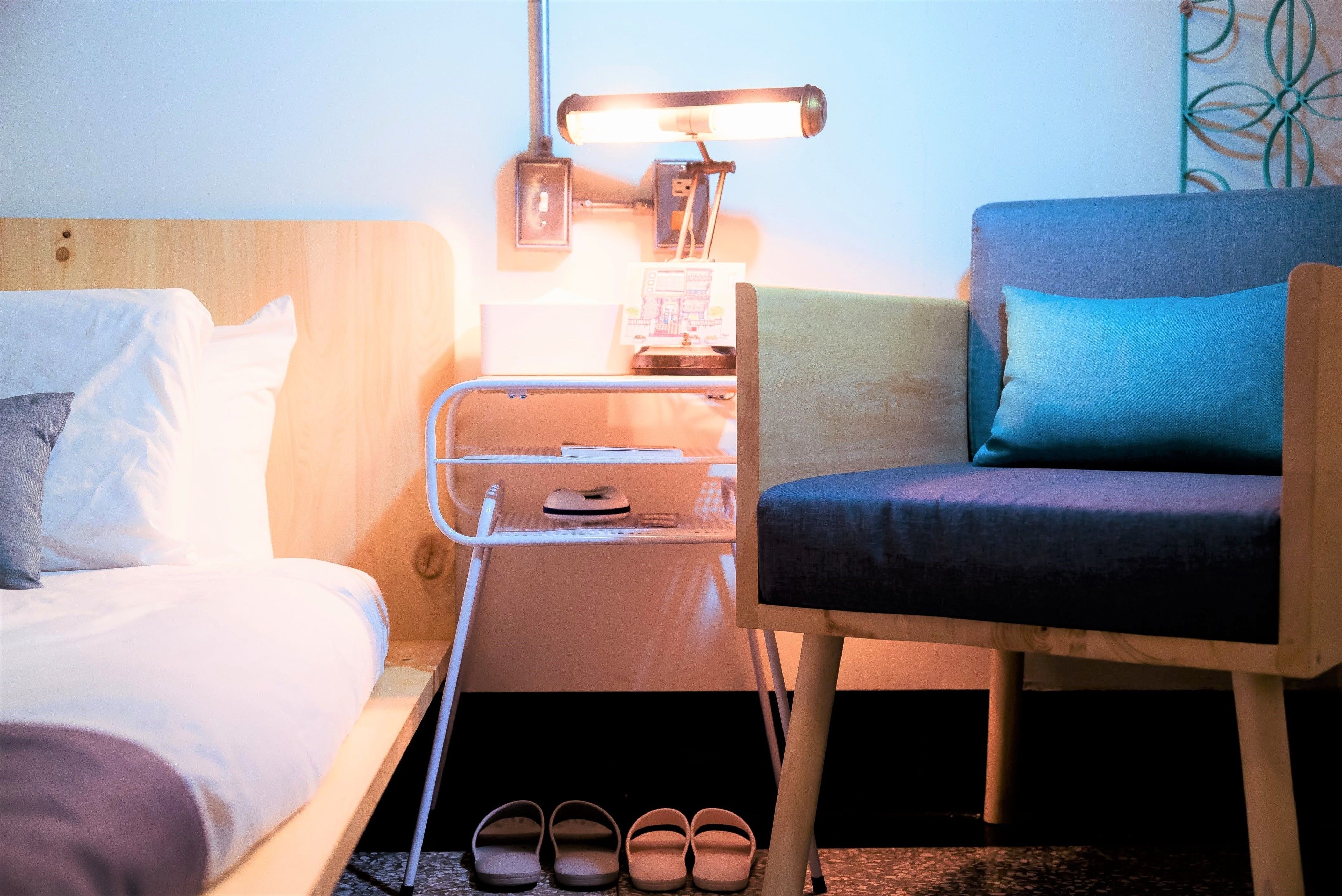 Une chambre d’hôtel avec un lit, une chaise, une table de chevet avec une lampe et un porte-chaussures.