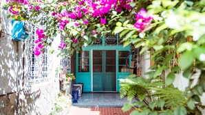 Een turquoise deur met een fiets aan de muur, een tafeltje en een blauwe stoel voor een gebouw.