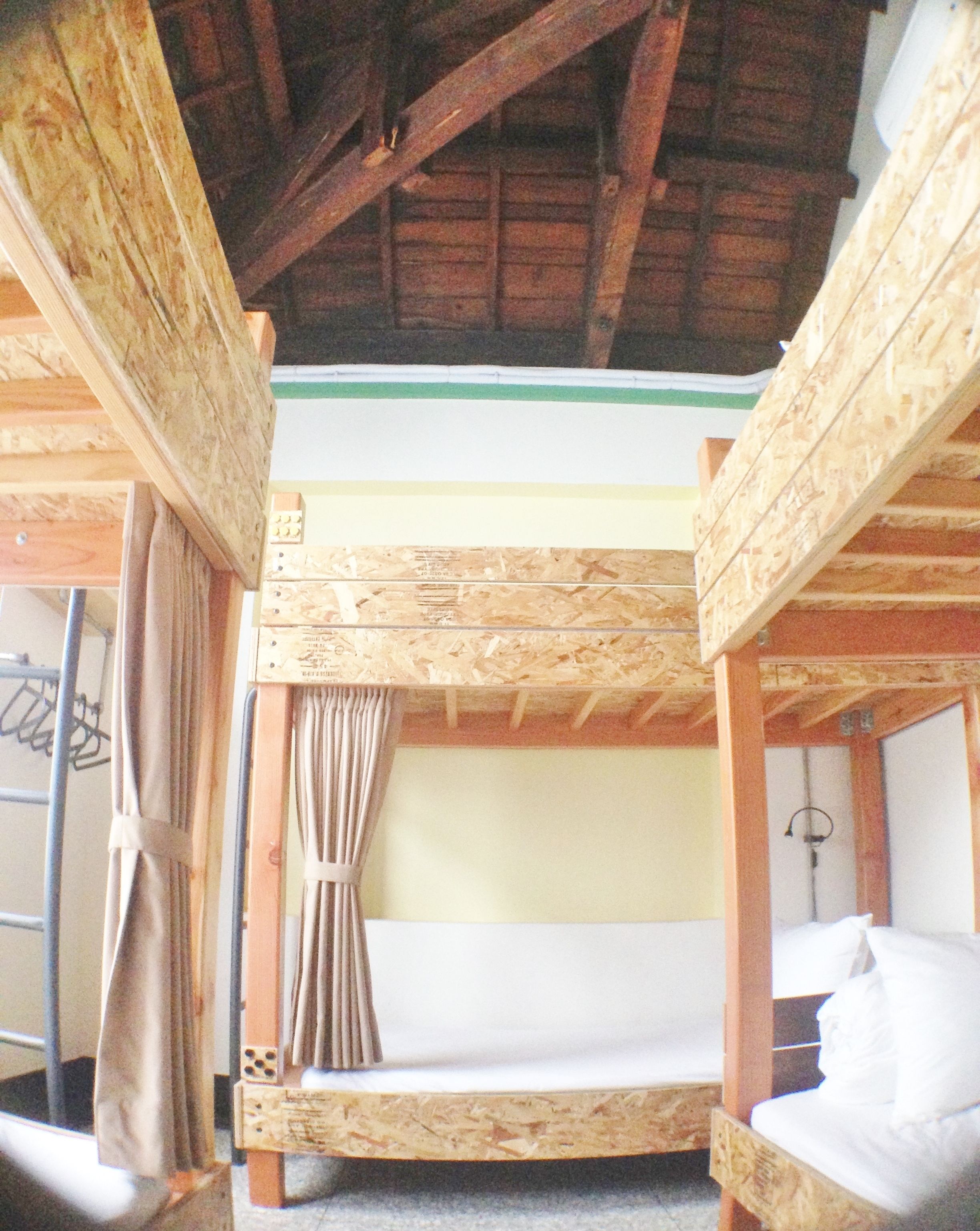 A bunk bed room with wooden beams and a green stripe on the wall.