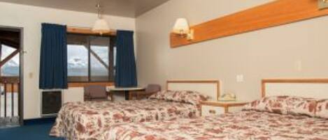 Habitación de hotel con dos camas, un escritorio y una ventana con cortinas.