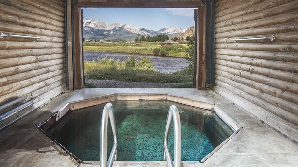 A log cabin with a hot tub and a view of mountains. - Mountain Village Lodge (Stanley)