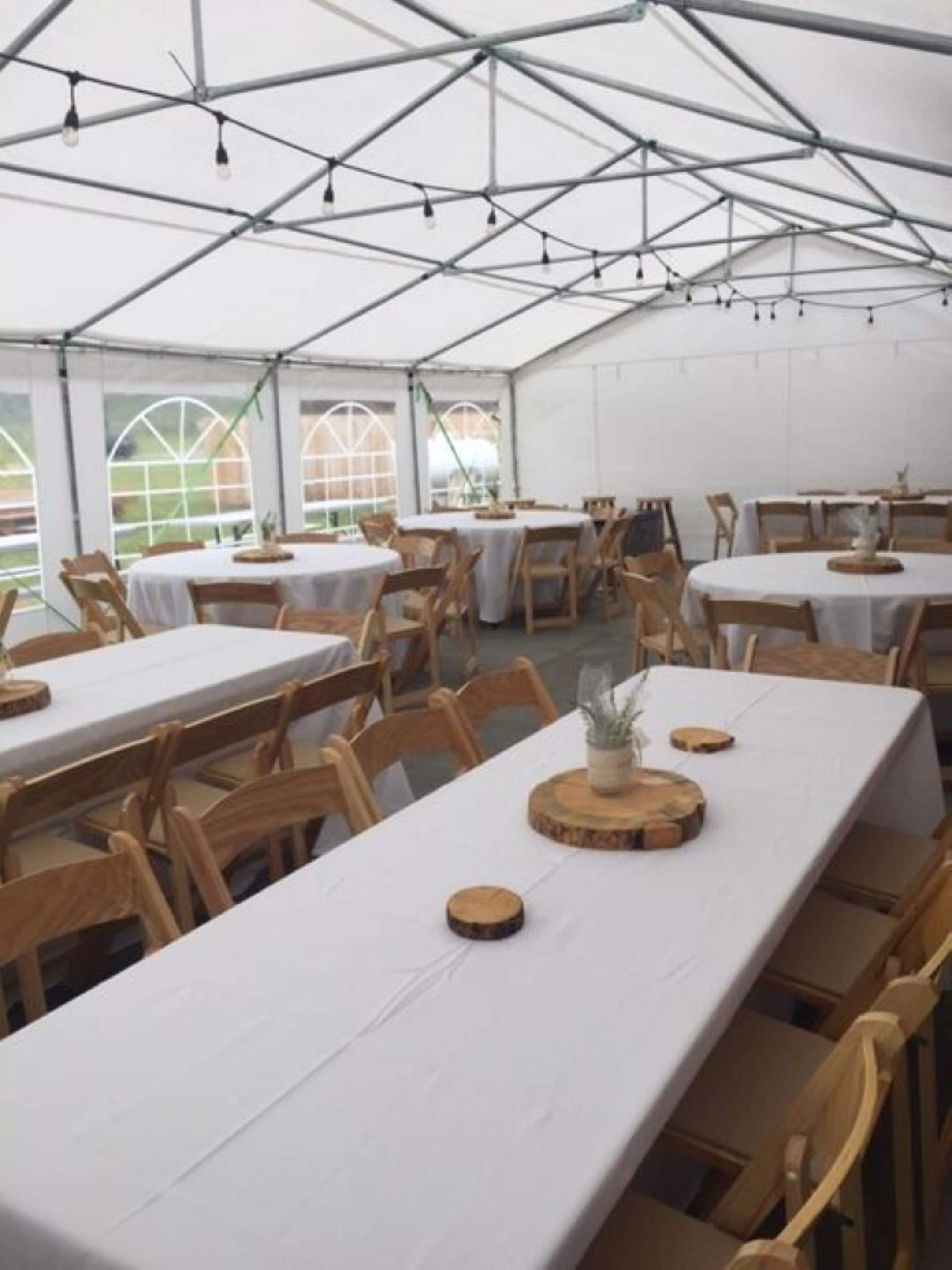 Un comedor con carpas, mesas y sillas, ventanas grandes y techo de estructura metálica.