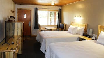 A hotel room with two beds, a desk, a chair, a TV, and a wooden dresser.