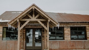 A rustic wooden building with a gabled roof and large windows. - Mountain Village Lodge (Stanley)
