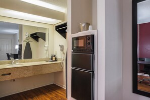 Una cocina compacta equipada con microondas, refrigerador y lavamanos con encimera.