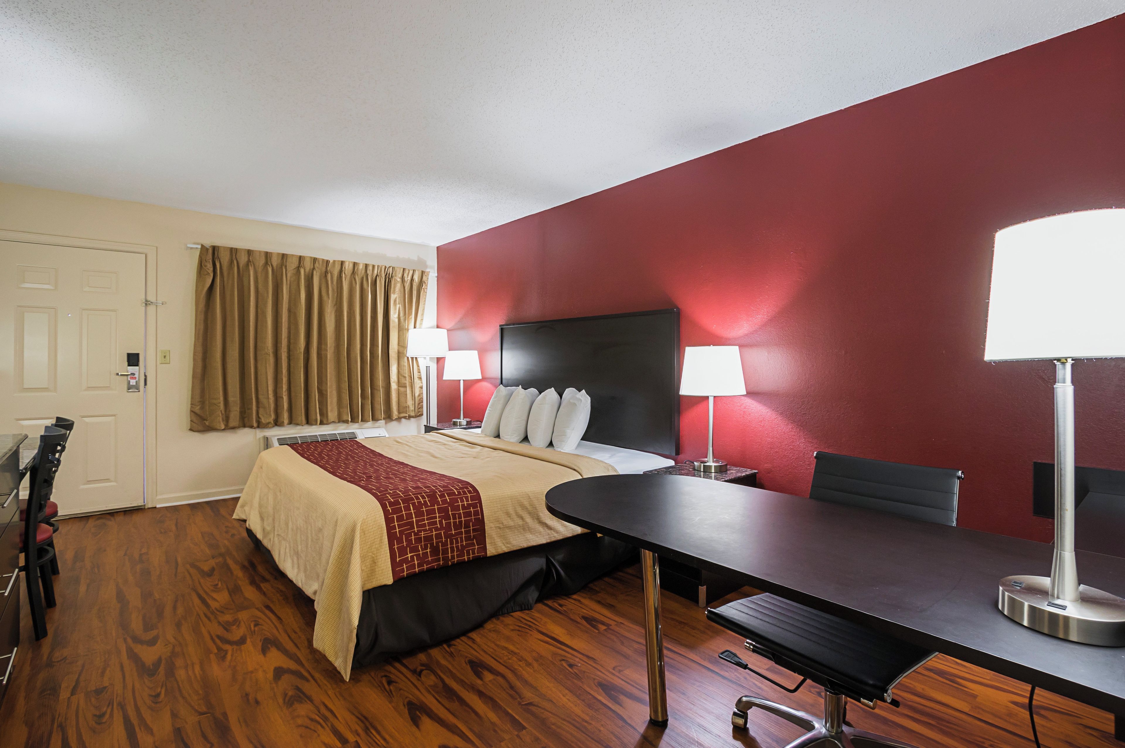 A hotel room with a bed, bedside lamps, a desk, and a chair.