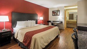 A hotel room with a bed, bedside tables, a desk, and a bathroom visible through an open door. - Red Roof Inn & Suites Scottsboro (Scottsboro)