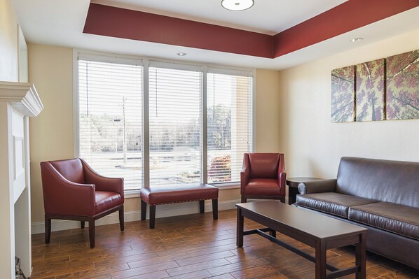 A living room with a sofa, two armchairs, a coffee table, and a large window with blinds.