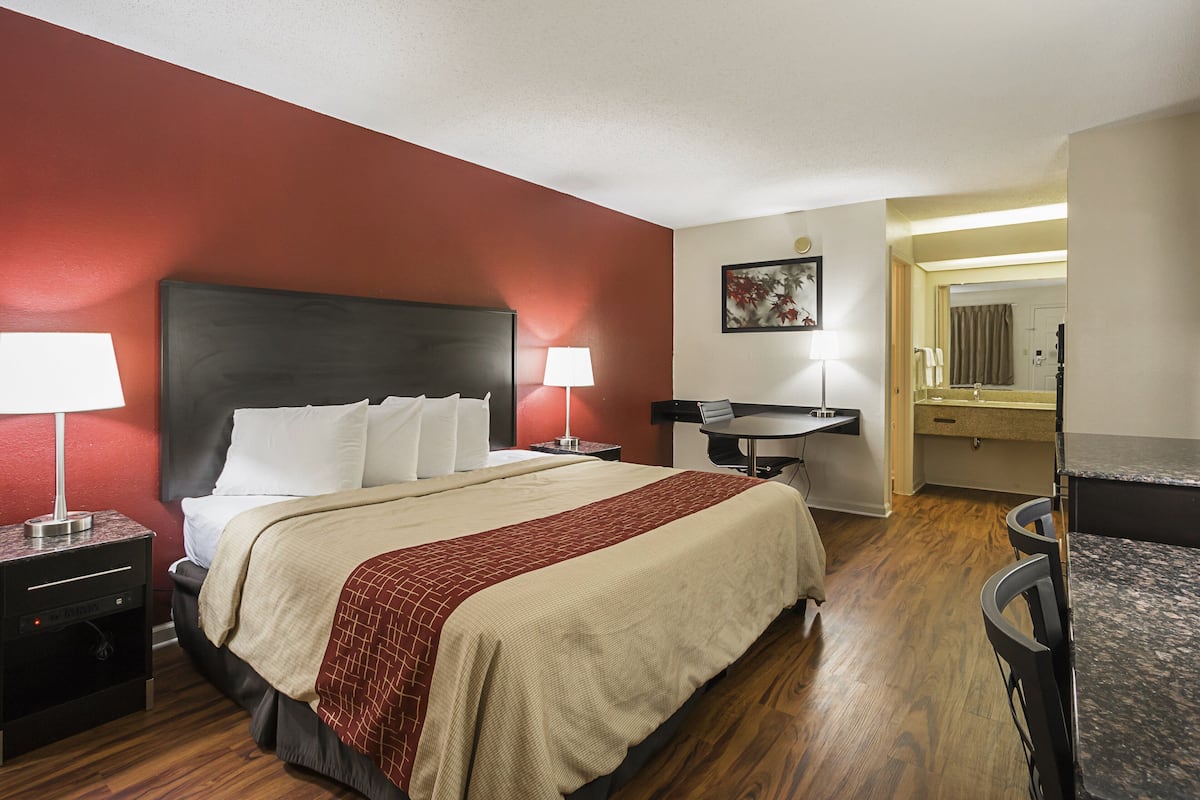 Una habitación de hotel con una cama grande, mesitas de noche, un escritorio y una silla.
