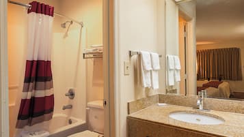 Un baño con cortina de ducha, bañera, inodoro y lavabo con espejo.