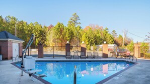 A rectangular swimming pool with a diving board, surrounded by a brick wall and a metal fence. - Red Roof Inn & Suites Scottsboro (Scottsboro)