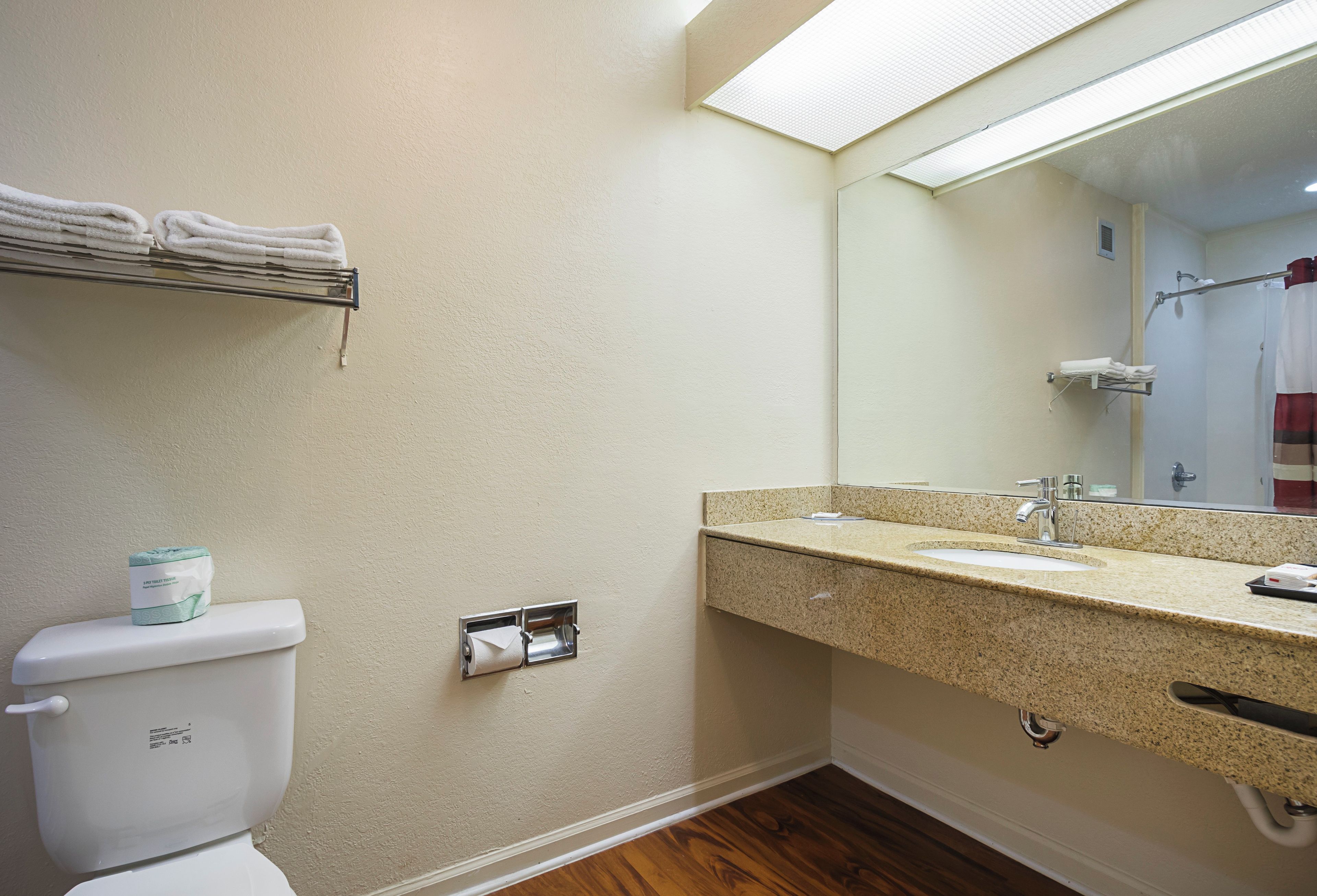 Une salle de bain comprenant des toilettes, un lavabo, un miroir et un porte-serviettes.