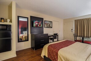 Una habitación de hotel con cama, escritorio, silla, televisión, armario y puerta.