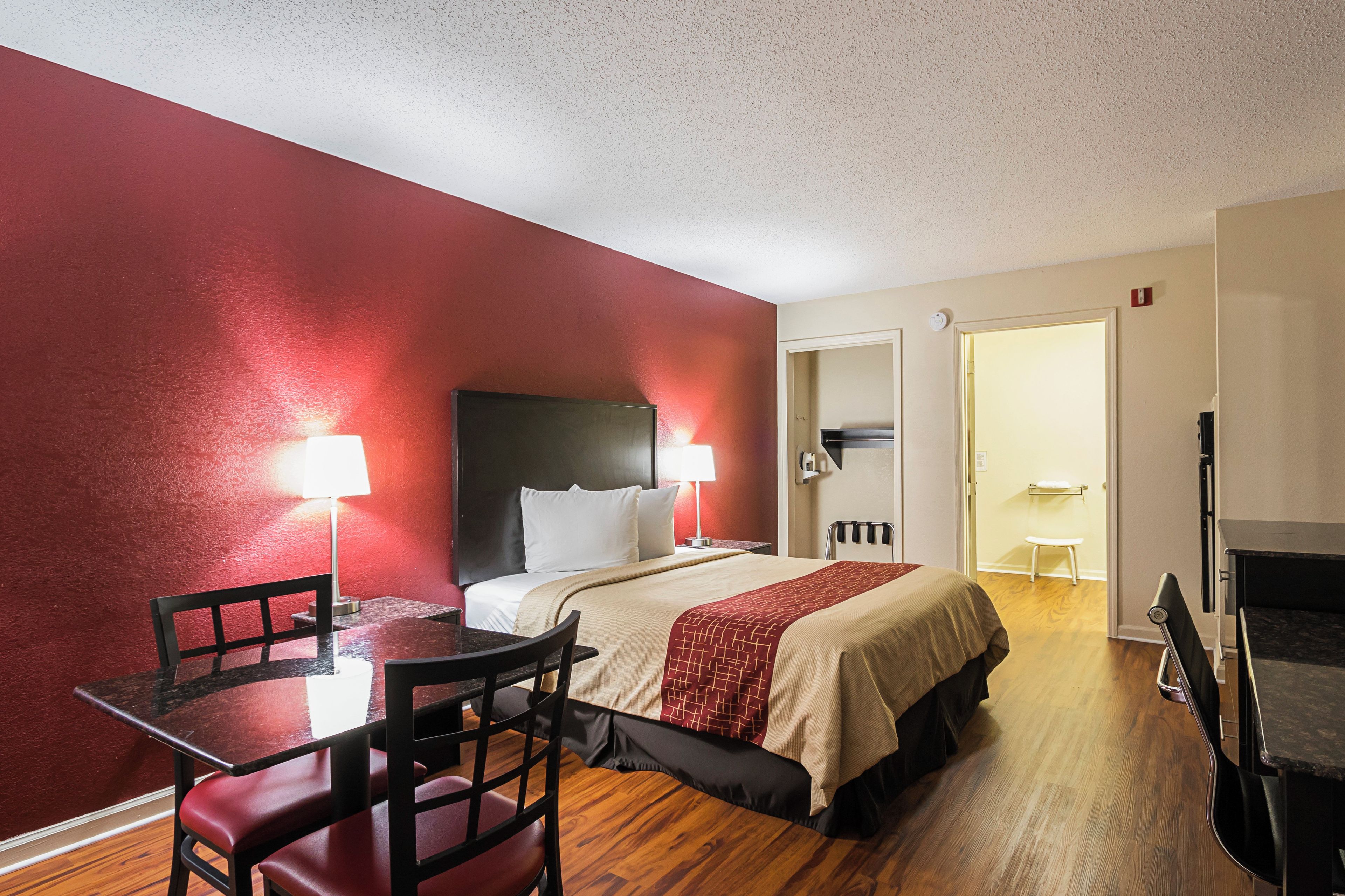 Une chambre d’hôtel comprenant un lit, un bureau avec une chaise, une lampe de table et un téléviseur.