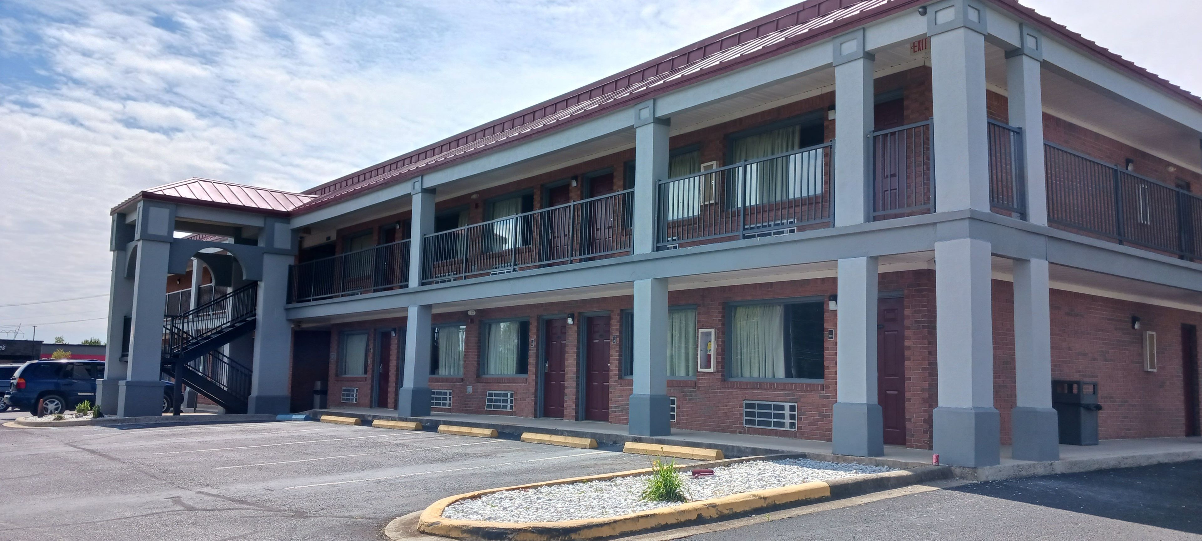 A multi-story building with a central atrium, large windows, and a parking lot in front.