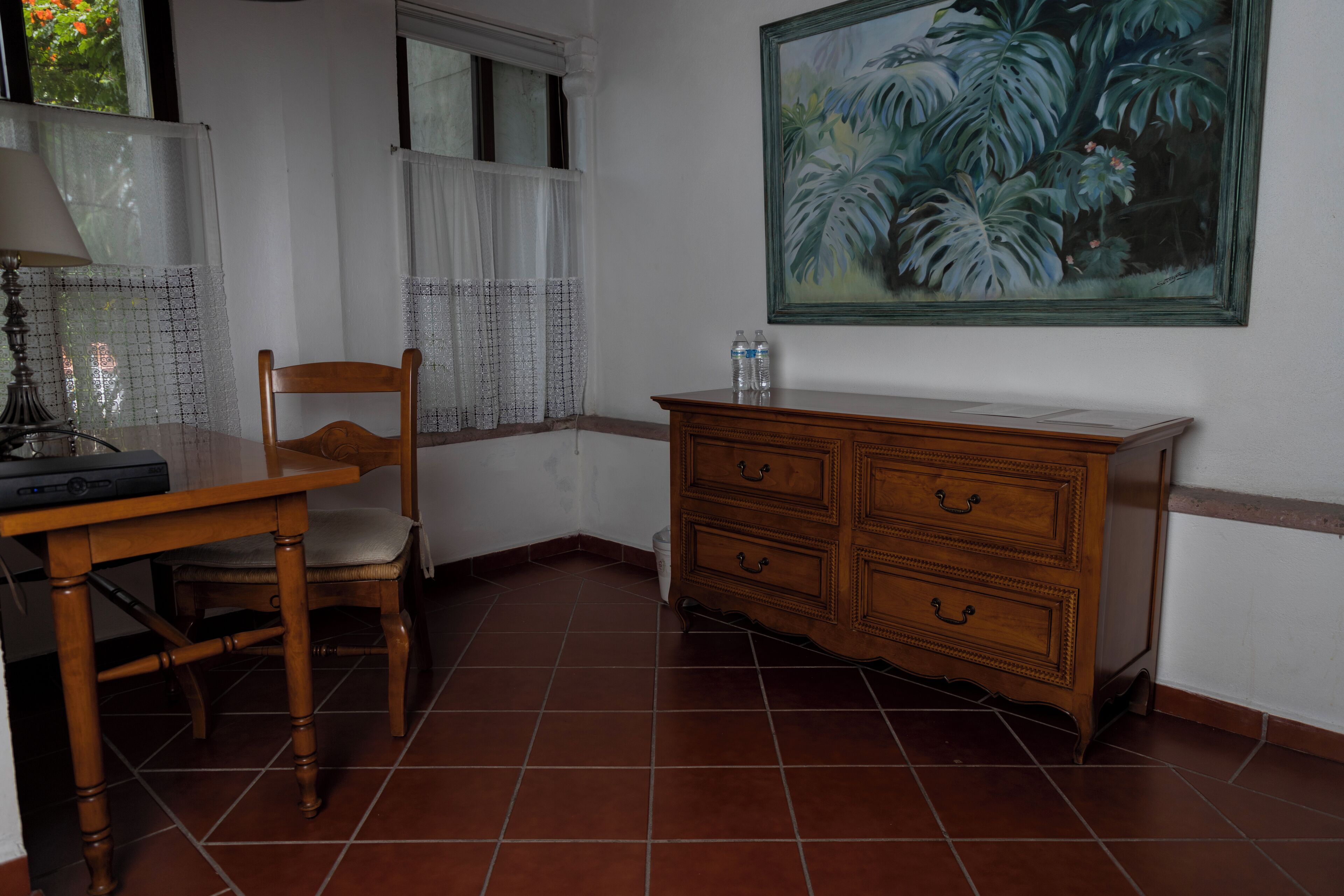 Una habitación con una mesa de madera, una silla, un armario de madera y un cuadro en la pared.
