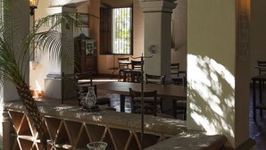 A dining area with a high ceiling, wooden beams, and a view of a room with a window. - Hotel Boutique Casa de Campo (Cuernavaca)