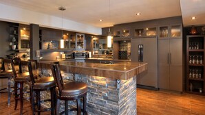 A modern kitchen with a central island, bar stools, and built-in appliances. - Le Chateau du Lac (West Kelowna)