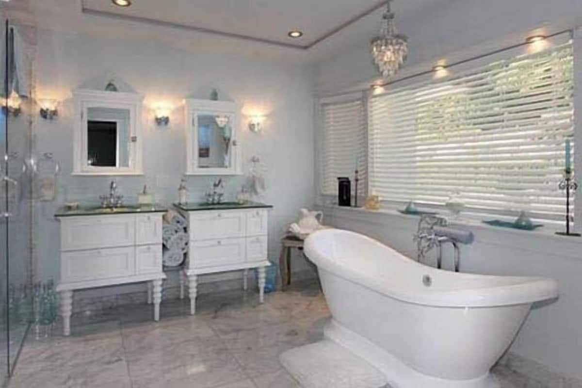 Un baño con una bañera independiente, una ducha con cerramiento de vidrio y un tocador doble con dos lavamanos.