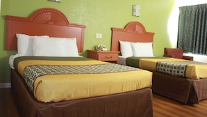 Habitación de hotel con dos camas, paredes verdes y suelo de madera.