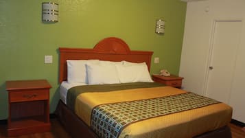 A hotel room with a wooden bed, green walls, and a white door.