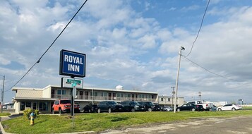 Un motel con un letrero que dice Royal Inn, varios coches estacionados y un área verde al frente.