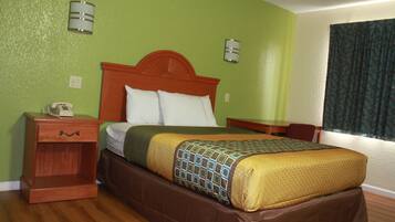 A hotel room with a wooden bed, green walls, and a window with curtains.