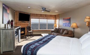 Habitación de hotel con cama, televisión, chimenea, sofá y vistas al mar.