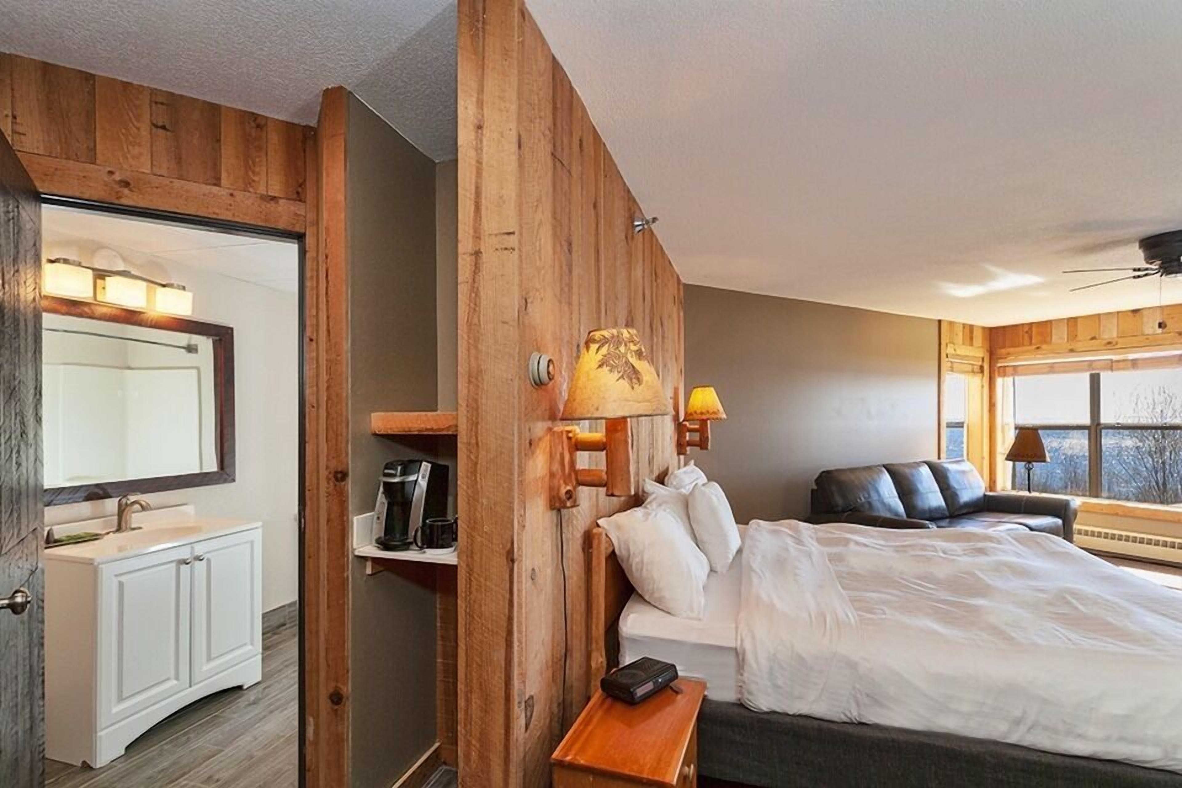 A bedroom with a bed, bedside table, lamp, and a window.