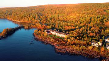 A large lodge with multiple buildings, a lake, and a forested area.