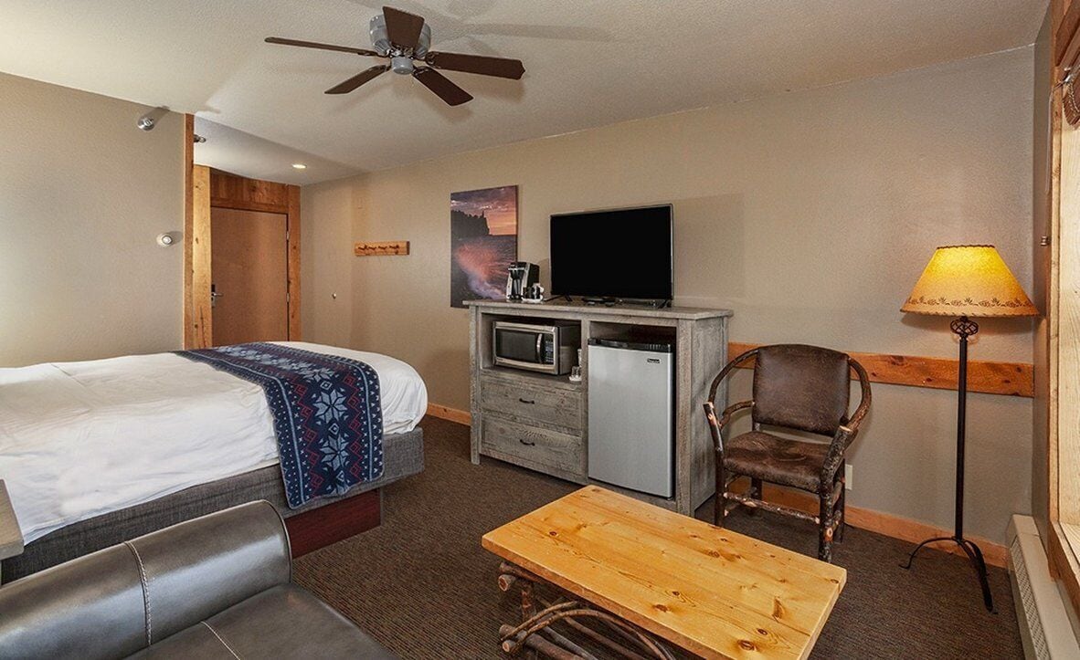 Une chambre d’hôtel équipée d’un lit, d’un bureau, d’une chaise, d’une télévision, d’un four à micro-ondes et d’un ventilateur de plafond.