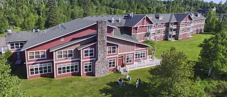 A multi-story building with a stone chimney, large windows, and a well-maintained lawn.