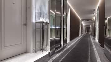 A modern hotel corridor with a carpeted floor, mirrored walls, and a number "602" visible on the floor.