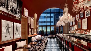 Zona de bar con piso a cuadros, diversas opciones de asientos y un amplio ventanal con vistas al exterior.