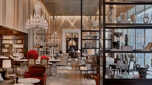 Un lobby de hotel lujoso con muebles elegantes, una lámpara de araña imponente y una exhibición de porcelana fina y cristalería.