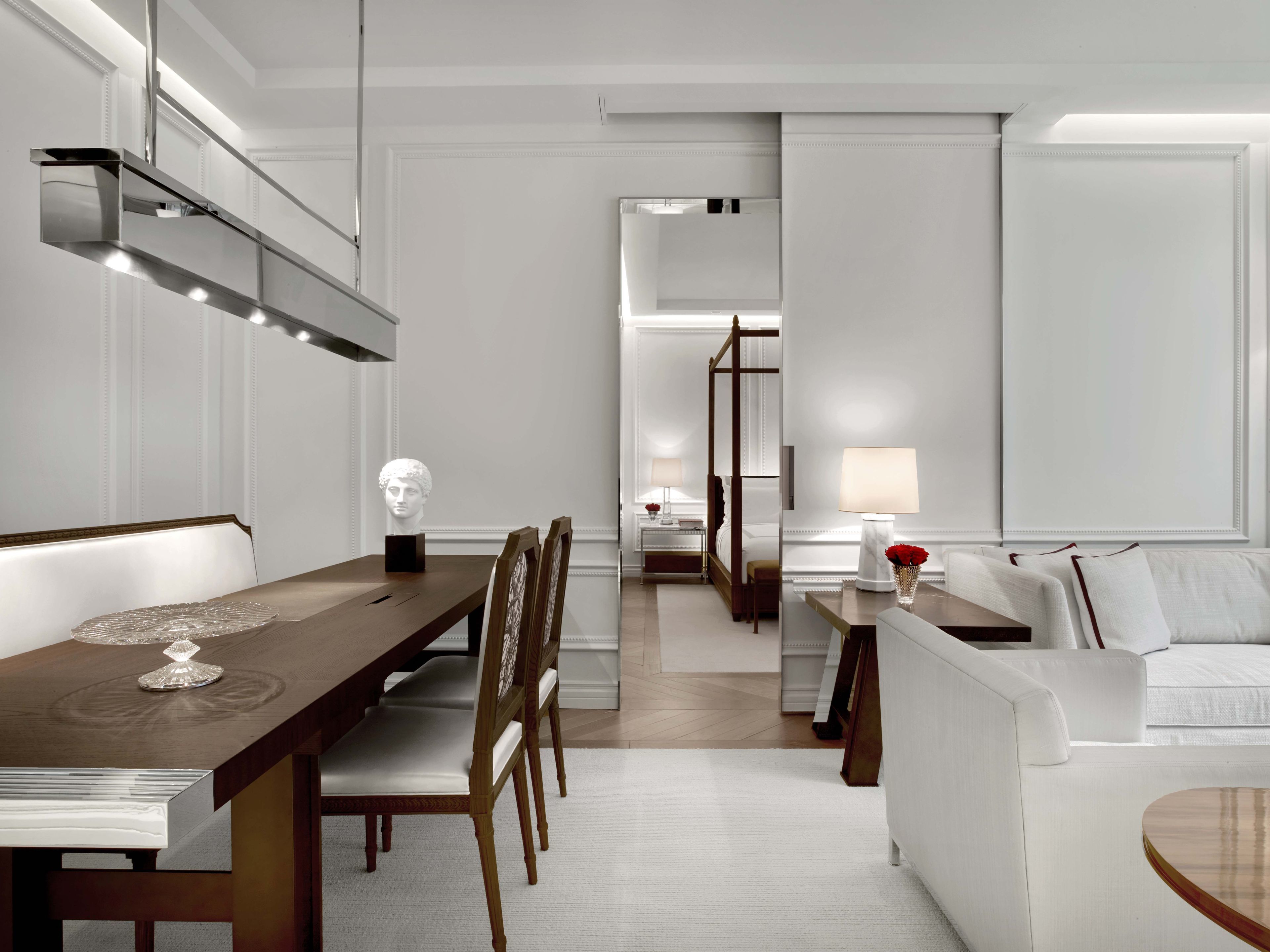 A modern hotel room with a dining area, a sofa, and a bed.