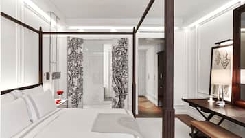 A modern hotel room with a four-poster bed, a wooden desk, and a large mirror.