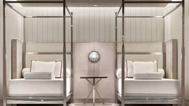 Una habitación de hotel moderna con piscina, dos camas, una mesita y un espejo grande.