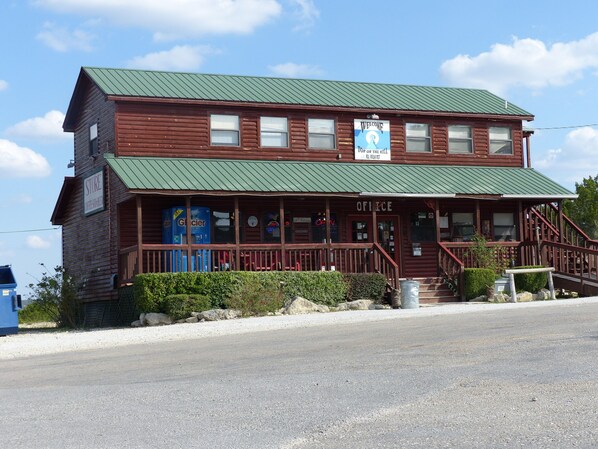 A two-story wooden building with a green roof, a store, and an office.
