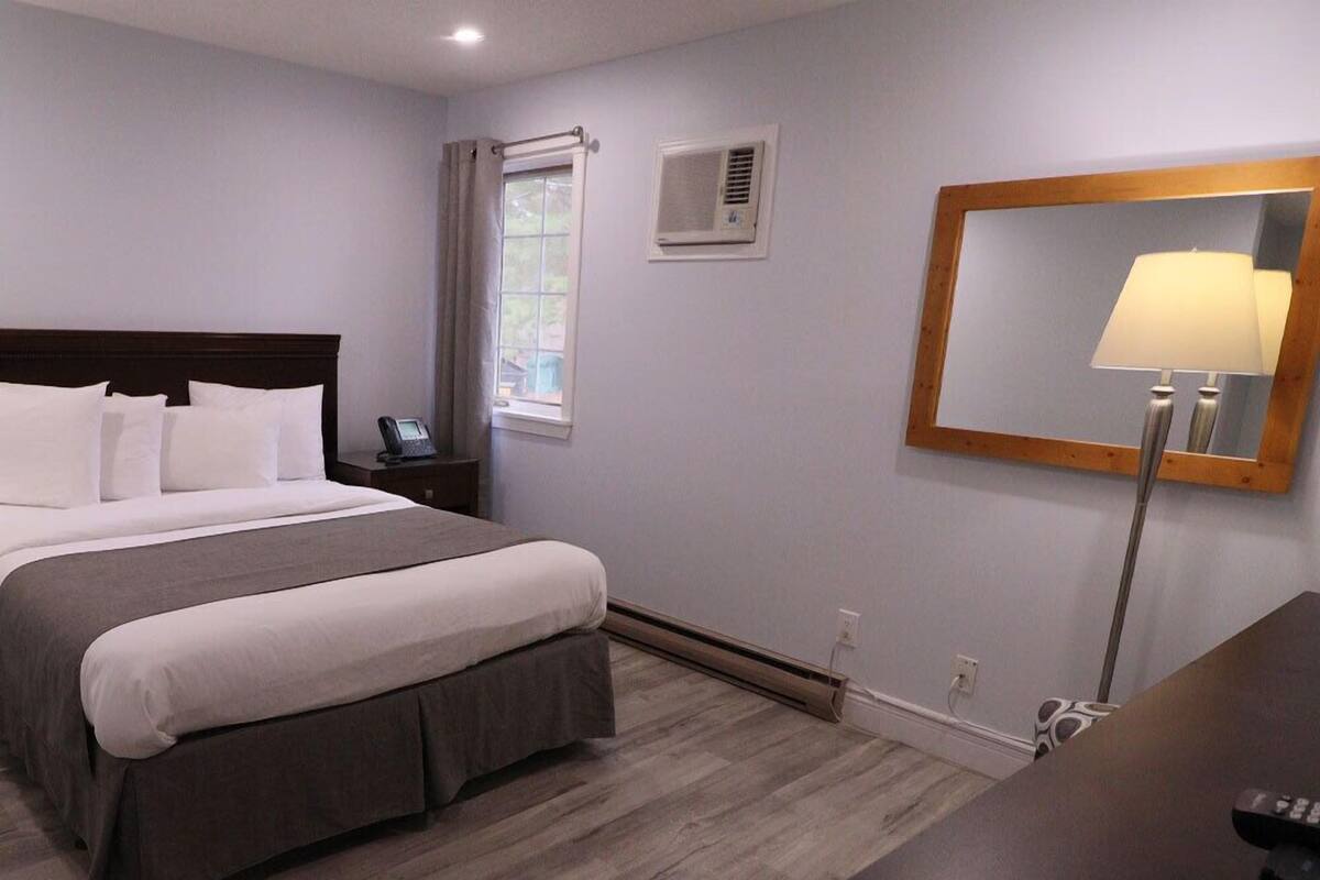 Une chambre d’hôtel avec un lit, une table de chevet, une lampe et un miroir au mur.