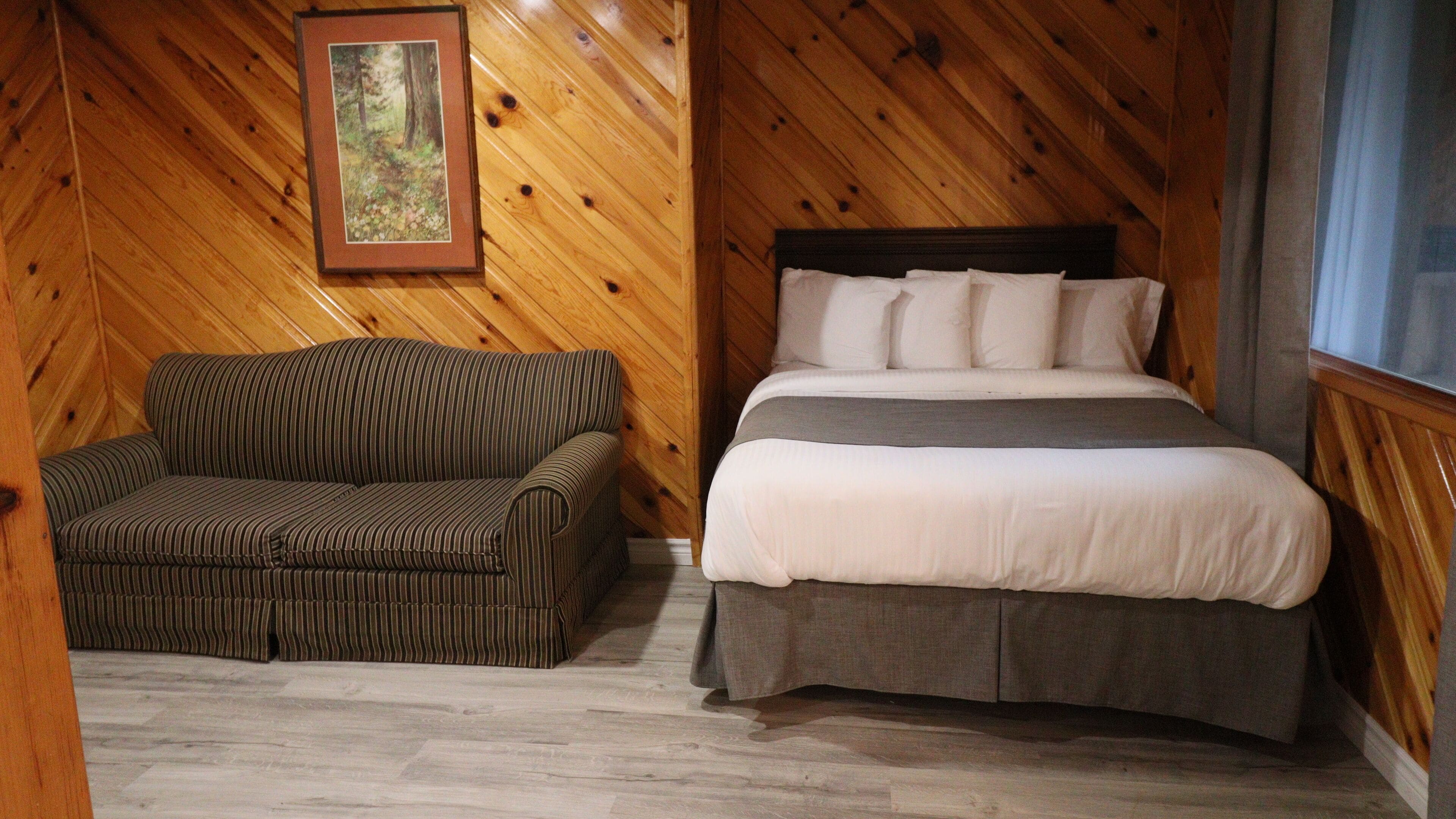 Una habitación con paneles de madera, una cama y un sofá a rayas.