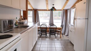 A compact kitchen with a stove, sink, and a dining table with chairs.